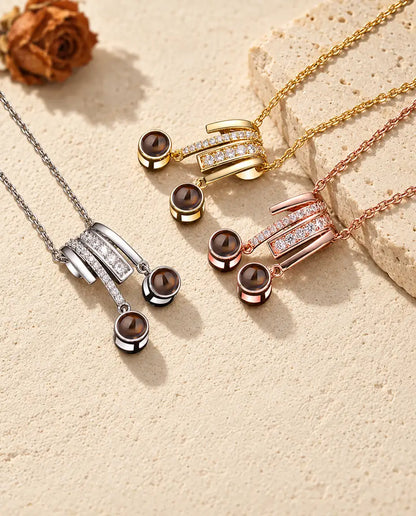 Pendentifs argenté, doré et couleur or rose à deux pierres réunis près d'une dalle de travertin