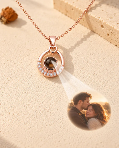 Collier goutte ajourée couleur or rose projetant une photo de couple sur le plâtre crème
