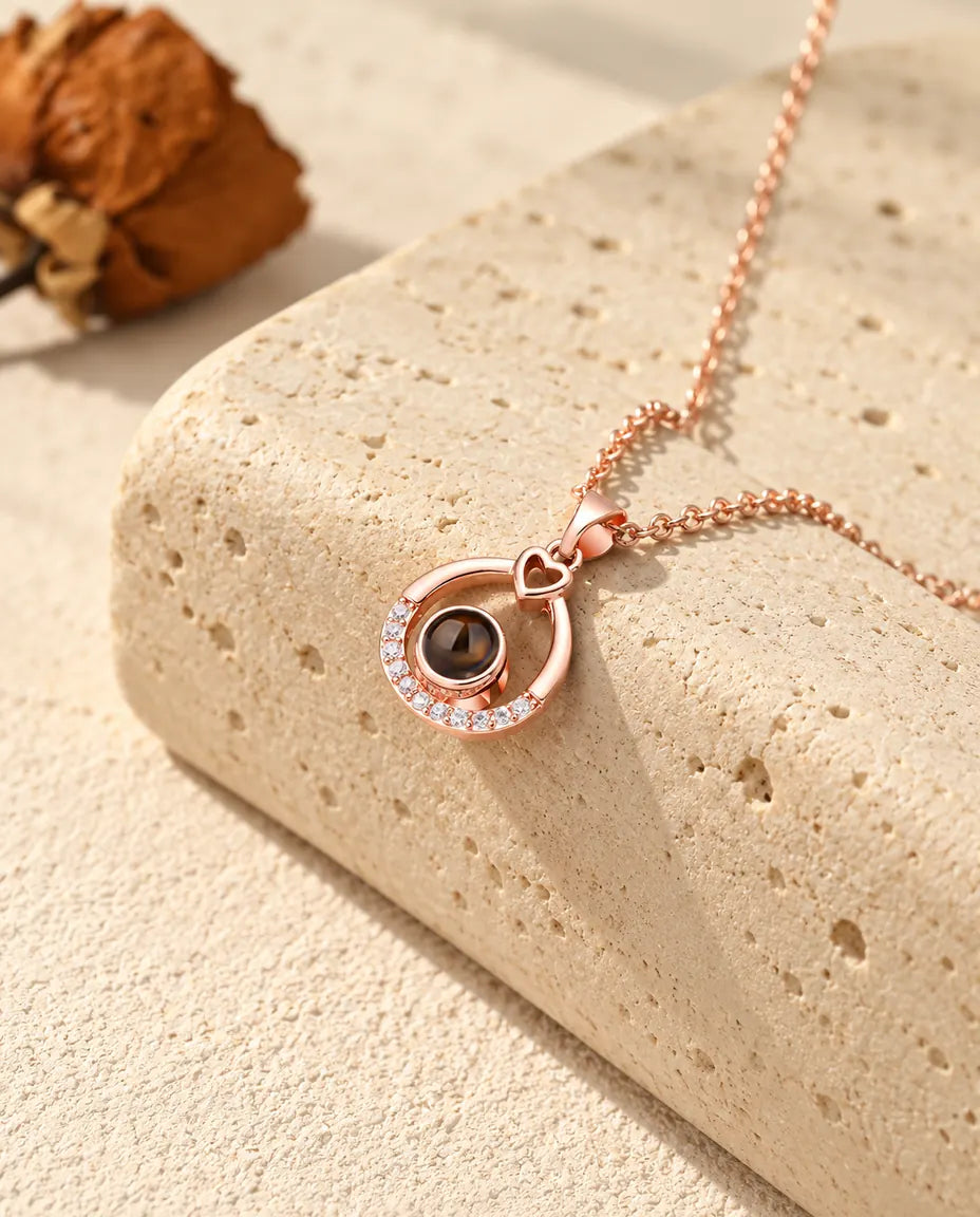 Collier goutte ajourée couleur or rose posé sur un bloc de travertin