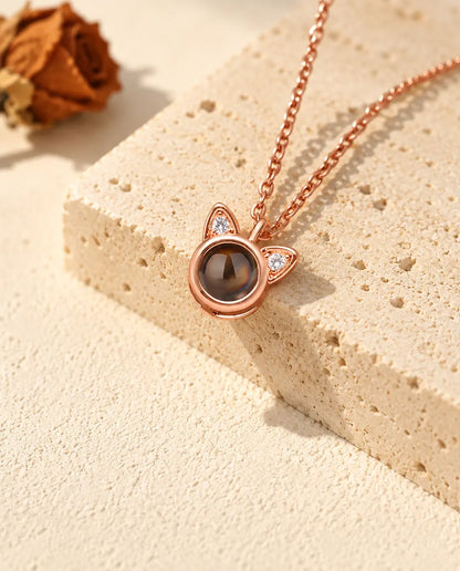 Collier oreilles de chat couleur or rose posé sur un bloc de travertin
