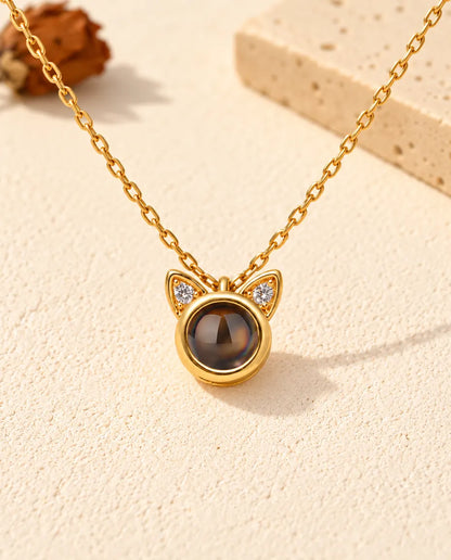 Vue de face du petit pendentif rond doré surmonté de deux oreilles de chat