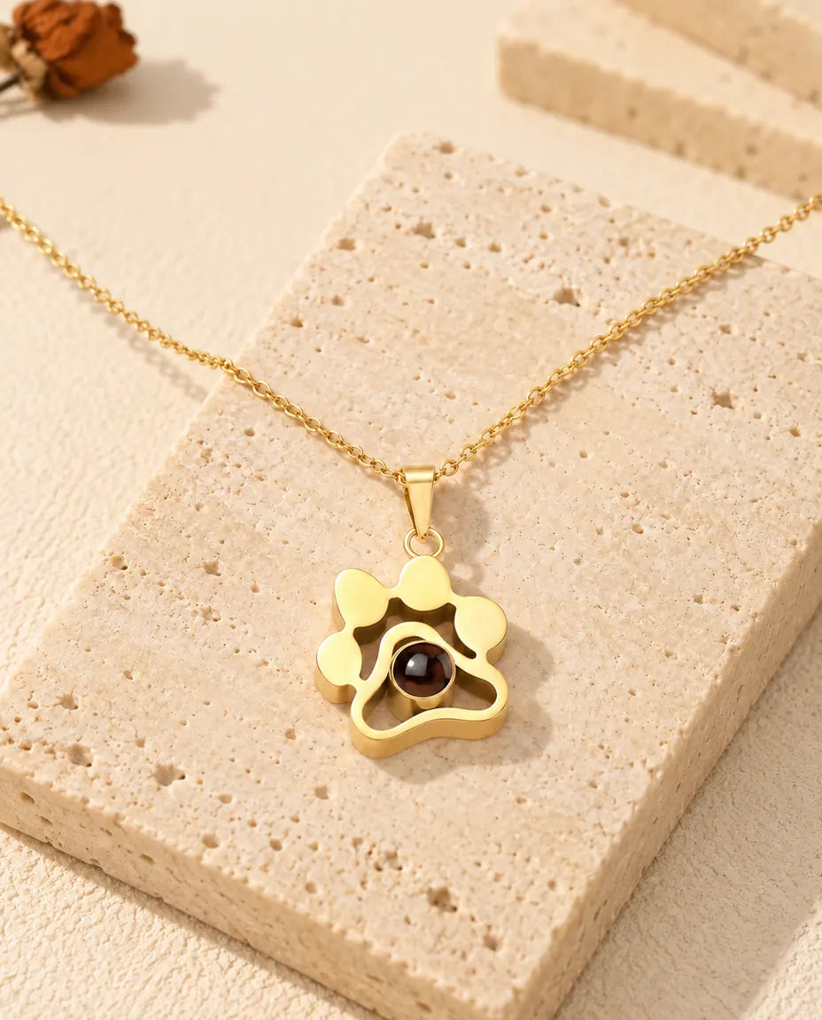 Collier patte doré posé sur un bloc de travertin
