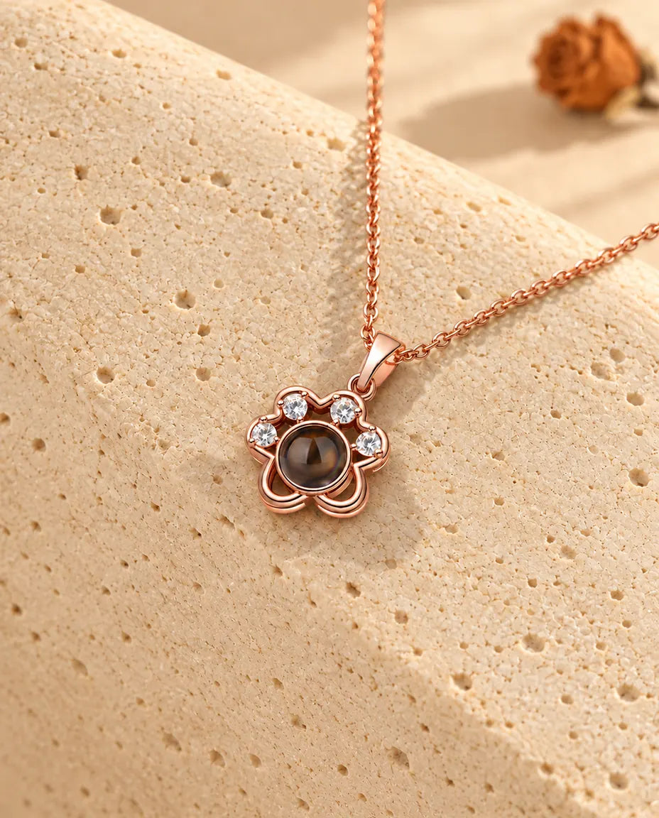 Collier patte couleur or rose posé sur du travertin