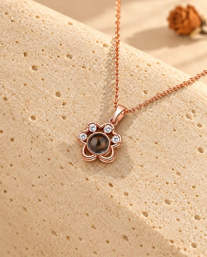 Collier patte couleur or rose posé sur du travertin