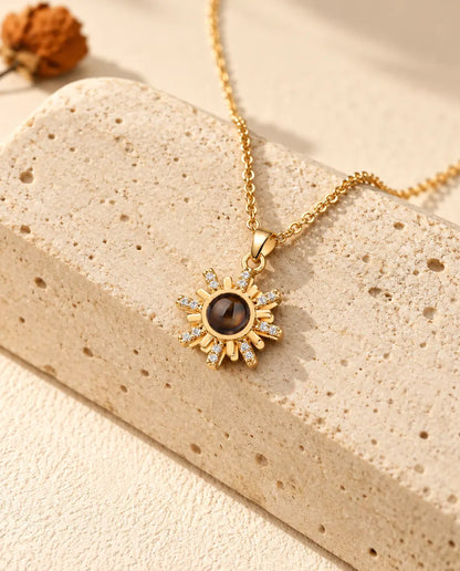 Collier soleil photo projection personnalisé doré posé sur un bloc de travertin