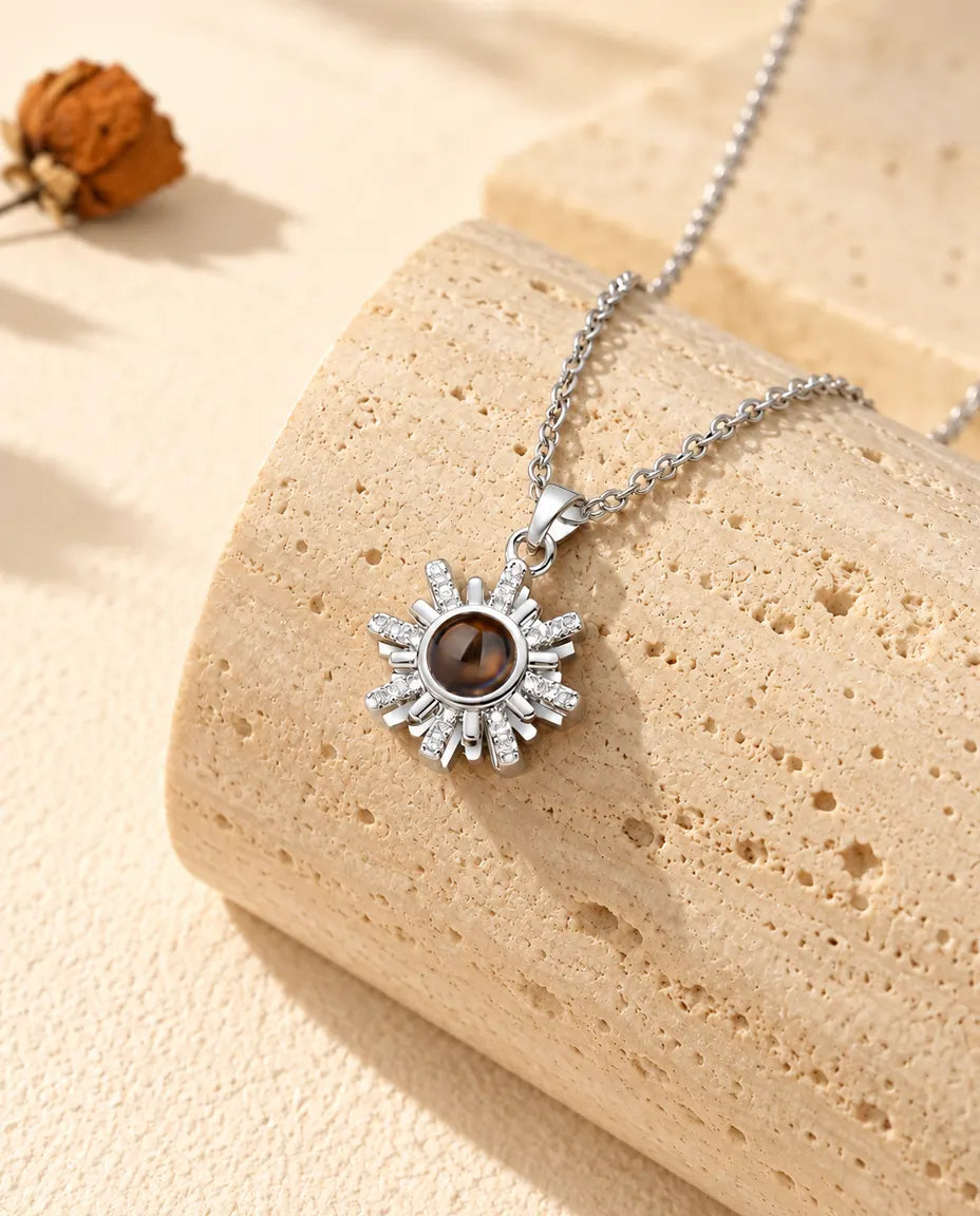 Collier soleil argenté avec photo dans la pierre sur un bloc de travertin