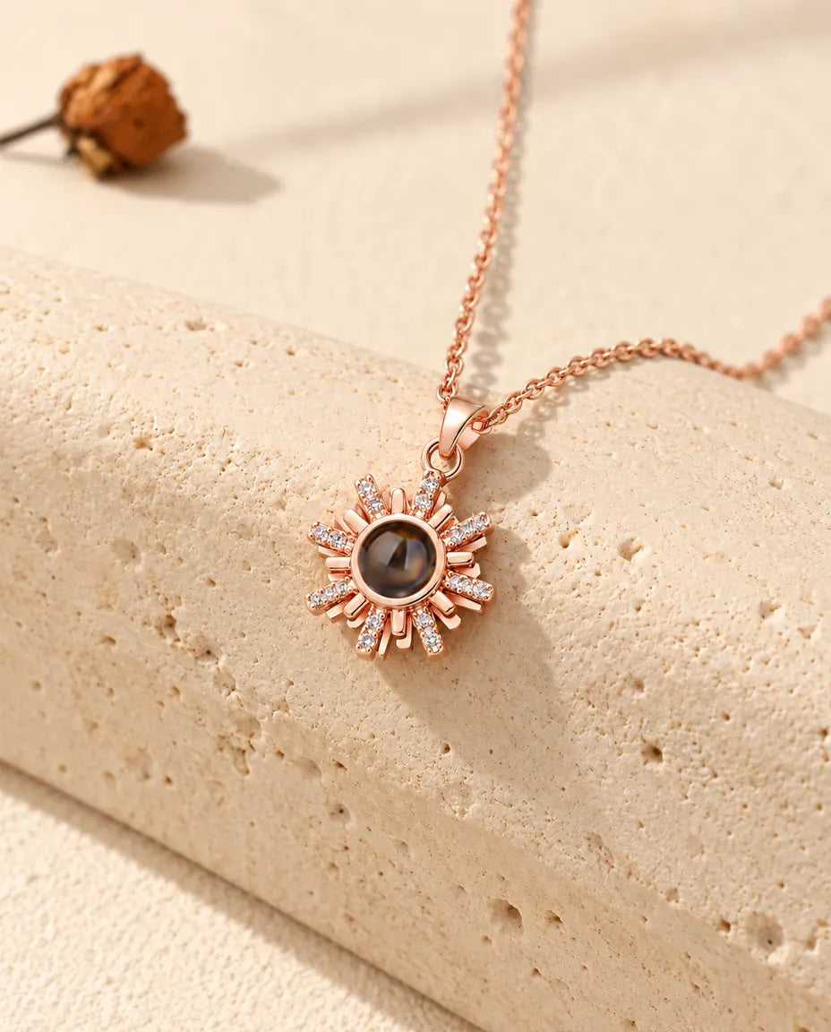 Collier soleil couleur or rose suspendu au-dessus d'un bloc de travertin