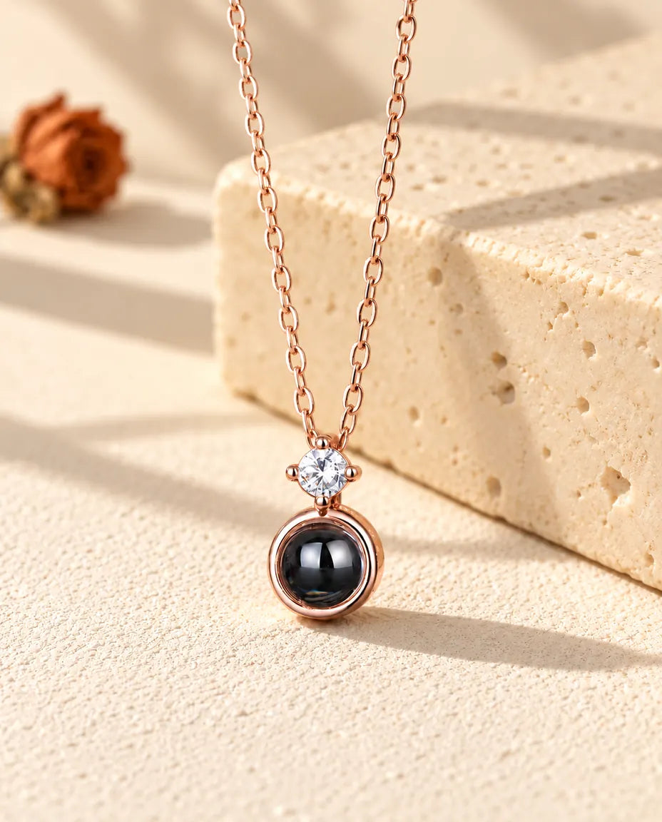 Collier solitaire couleur or rose suspendu devant un bloc de travertin