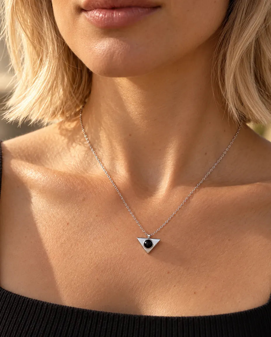 Femme en haut noir portant le collier triangle minimaliste argenté