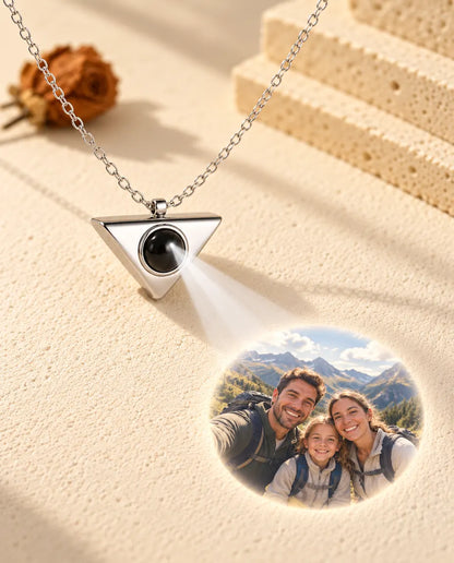 Collier triangle argenté projetant une photo de famille en randonnée sur le plâtre crème