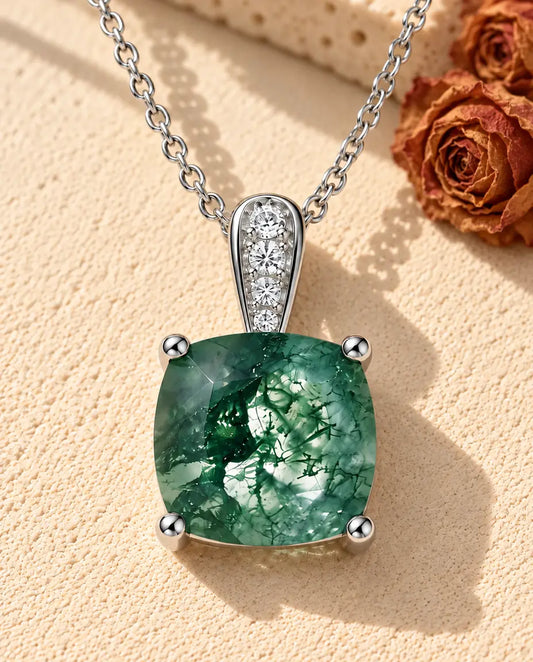 Collier Solitaire Agate Mousse en Argent 925 - posé sur une surface claire texturée près d’un bloc de travertin