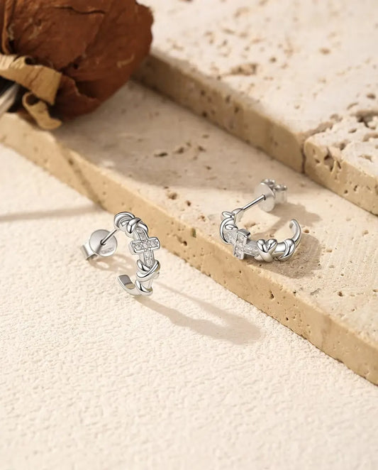 Boucles d’Oreilles Créoles Croix Moissanite en Argent 925 - la paire posée côte à côte sur une surface claire texturée