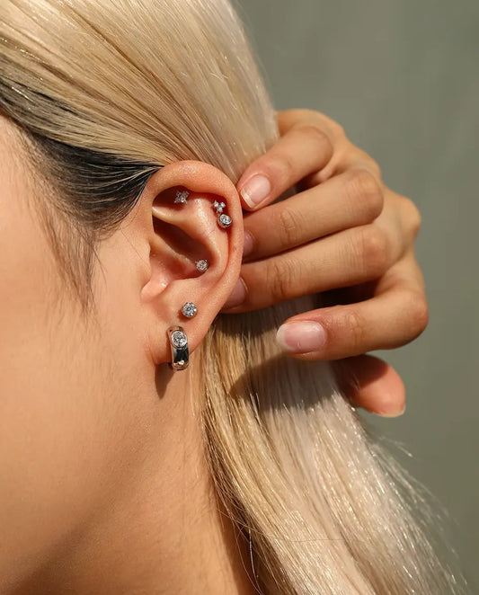 Boucles d’Oreilles Créoles Huggie Moissanite Ovale en Argent 925 - portée par un mannequin qui dégage ses cheveux derrière l’oreille
