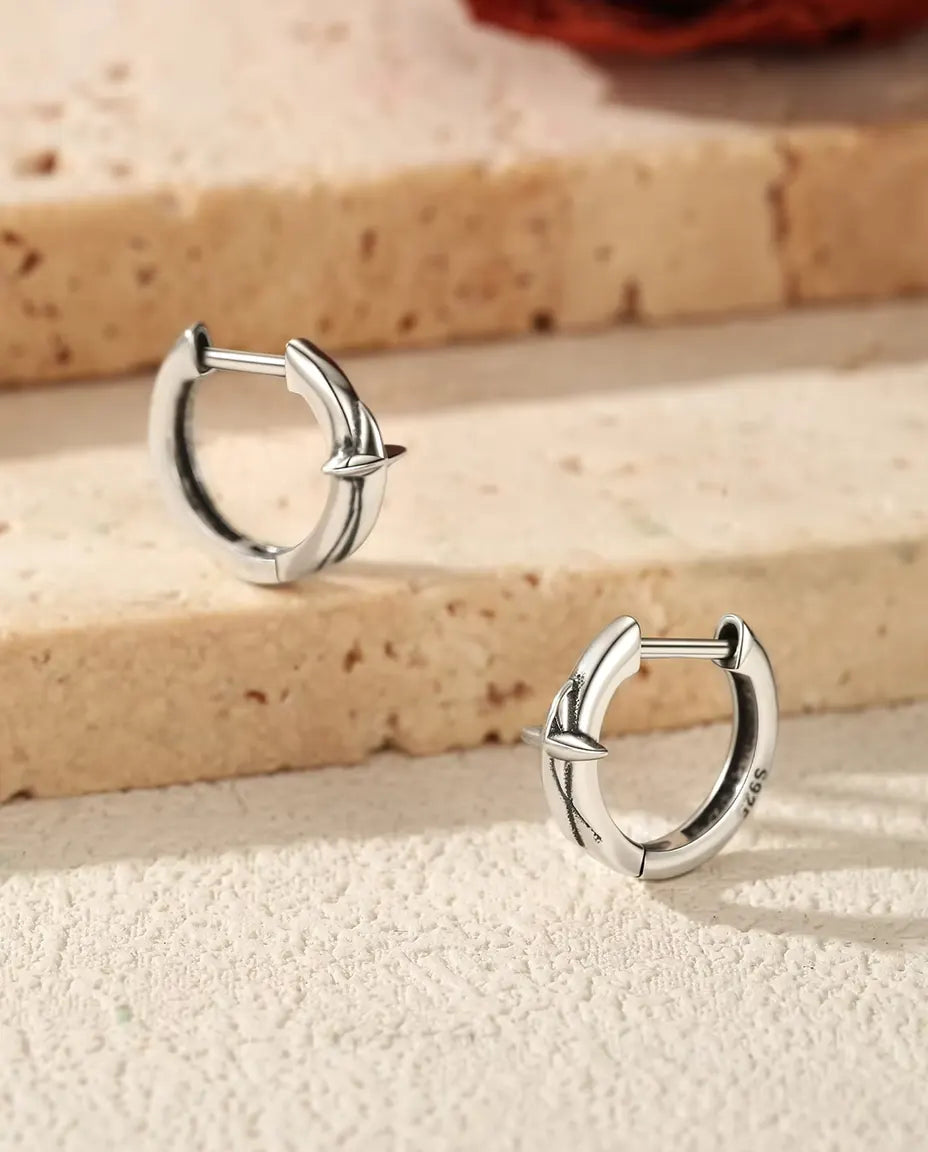 Boucles d’Oreilles Créoles Huggie Étoile en Argent 925 - la paire posée sur des marches en travertin