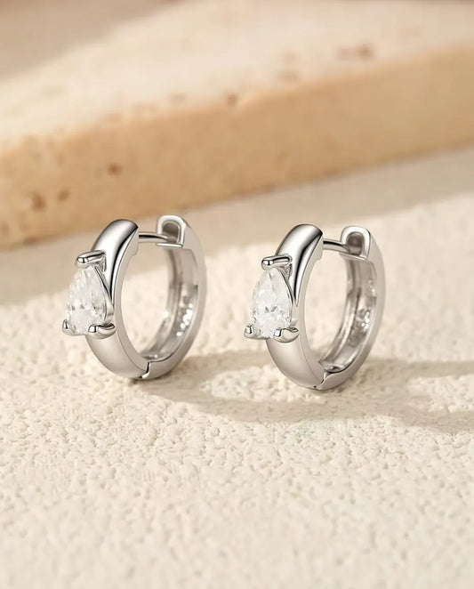 Boucles d’Oreilles Créoles Huggie Moissanite Poire en Argent 925 - la paire debout côte à côte sur une surface claire texturée