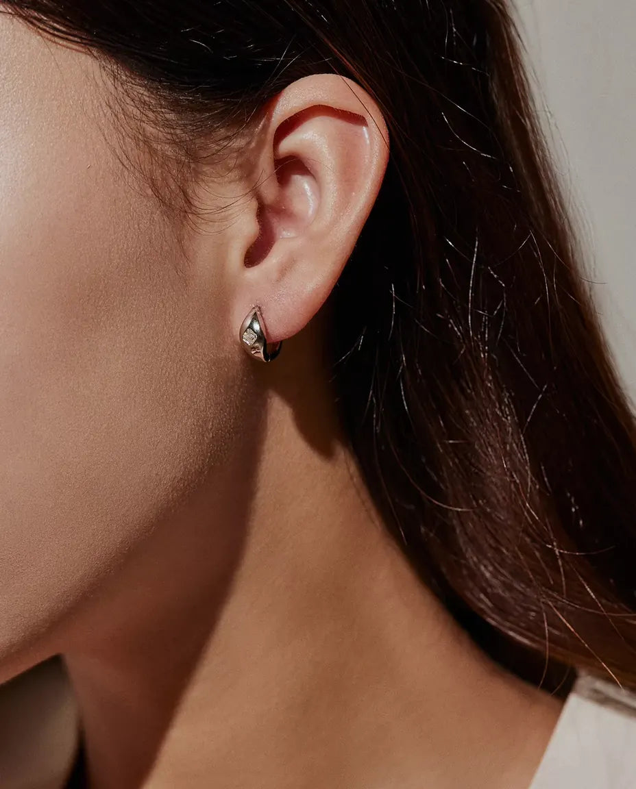 Boucles d’Oreilles Créoles Huggie Moissanite Taille Asscher en Argent 925 - portées à l’oreille par un mannequin, vue de profil