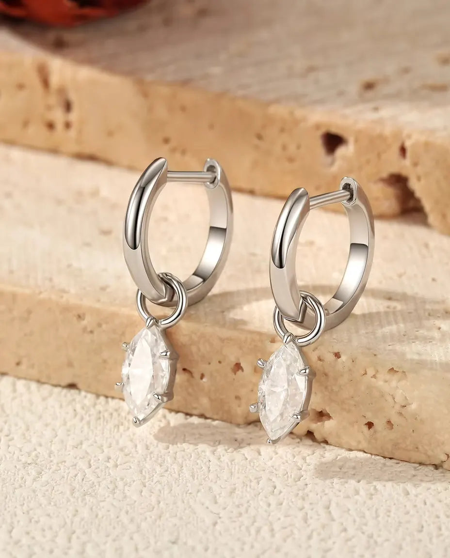 Boucles d’Oreilles Créoles Huggie à Pampille Moissanite Marquise en Argent 925 - la paire posée sur des marches en travertin