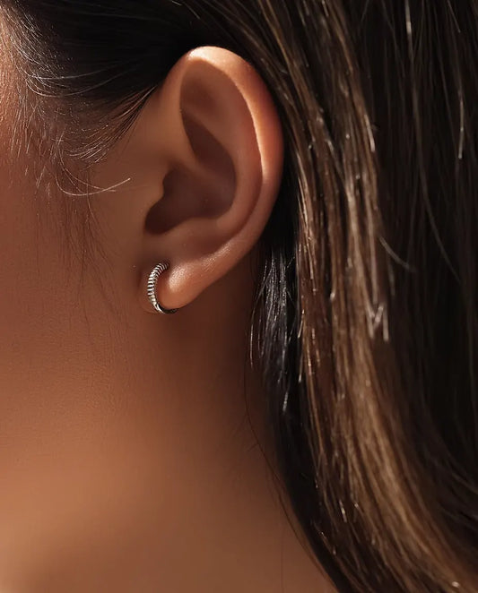 Boucles d’Oreilles Créoles Huggie Striées en Argent 925 - portées à l’oreille par un mannequin, gros plan