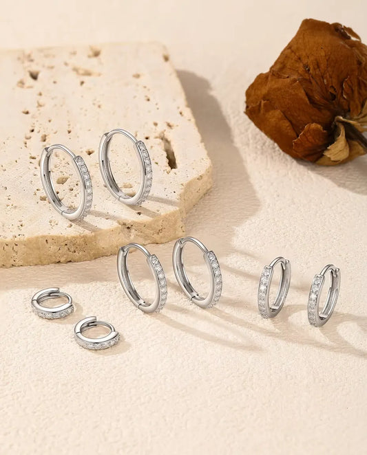 Boucles d’Oreilles Créoles Moissanite en Argent 925 - les cinq tailles disposées sur une surface claire près d’une dalle de travertin