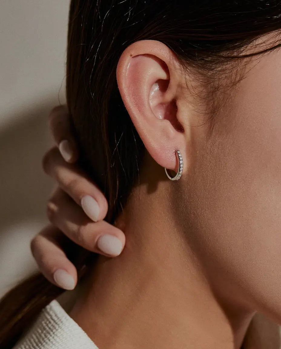 Boucles d’Oreilles Créoles Moissanite en Argent 925 - portées à l’oreille par un mannequin, main retenant ses cheveux