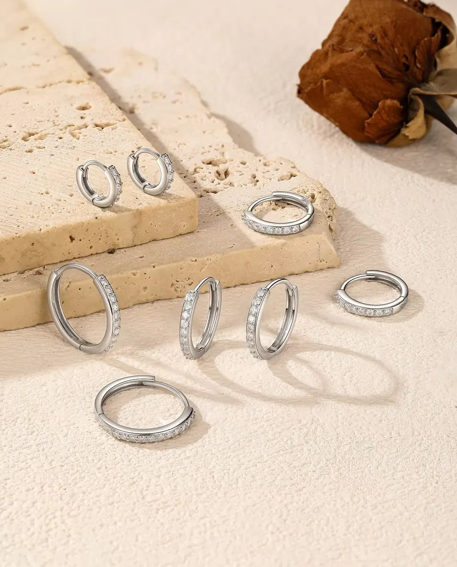 Boucles d’Oreilles Créoles Moissanite en Argent 925 - cinq tailles réparties sur une dalle de travertin et une surface claire
