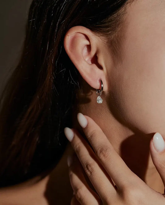 Boucles d’Oreilles Créoles Moissanite Poire en Argent 925 - portées à l’oreille par un mannequin, main près du visage
