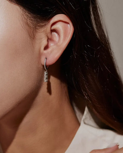 Boucles d’Oreilles Créoles Pendantes Trois Moissanites en Argent 925 - portées à l’oreille par un mannequin, gros plan