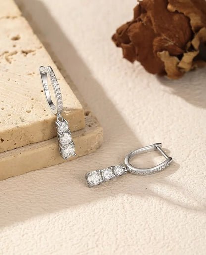 Boucles d’Oreilles Créoles Pendantes Trois Moissanites en Argent 925 - une boucle suspendue à une dalle de travertin, l’autre posée à côté