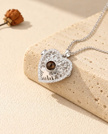 Collier médaillon cœur arbre de vie personnalisé argenté avec pierre de projection brune, posé sur un bloc de travertin