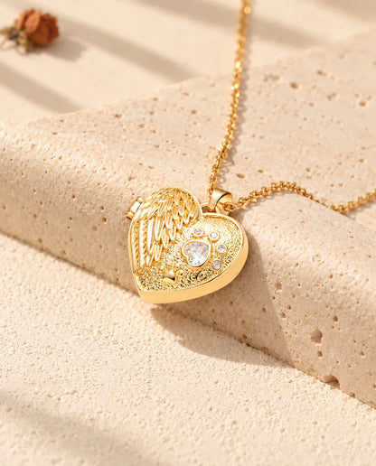 Collier médaillon photo cœur aile d'ange et patte doré posé sur un bloc de travertin