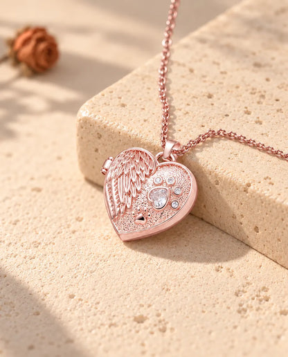 Collier médaillon photo cœur aile d'ange et patte couleur or rose sur travertin au soleil chaud
