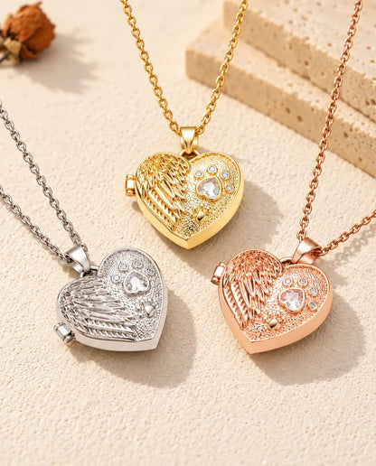 Les trois couleurs du collier médaillon photo cœur aile d'ange et patte disposées sur du plâtre