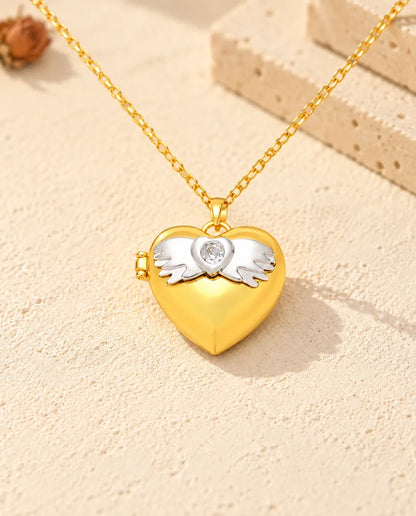 Médaillon photo cœur ailes d'ange doré vu de face, avec le motif du couvercle et la charnière