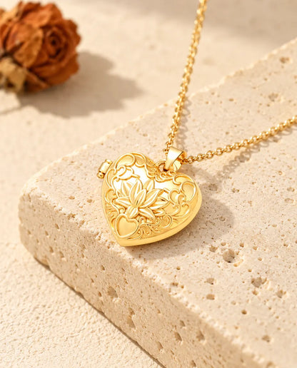 Collier médaillon photo cœur fleur de lotus doré posé sur un bloc de travertin