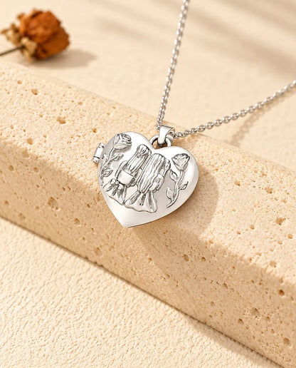 Collier personnalisé médaillon photo cœur sœurs, couleur argentée, posé contre un bloc de travertin