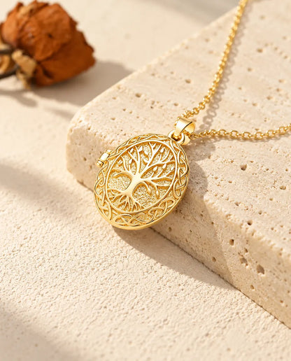 Collier médaillon ovale arbre de vie doré posé sur le bord d'un bloc de travertin