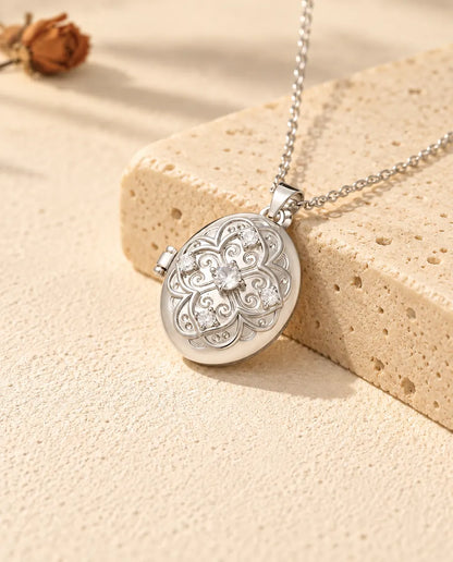 Médaillon photo ovale personnalisé argenté à fleur filigranée et zircons, appuyé contre un bloc de travertin