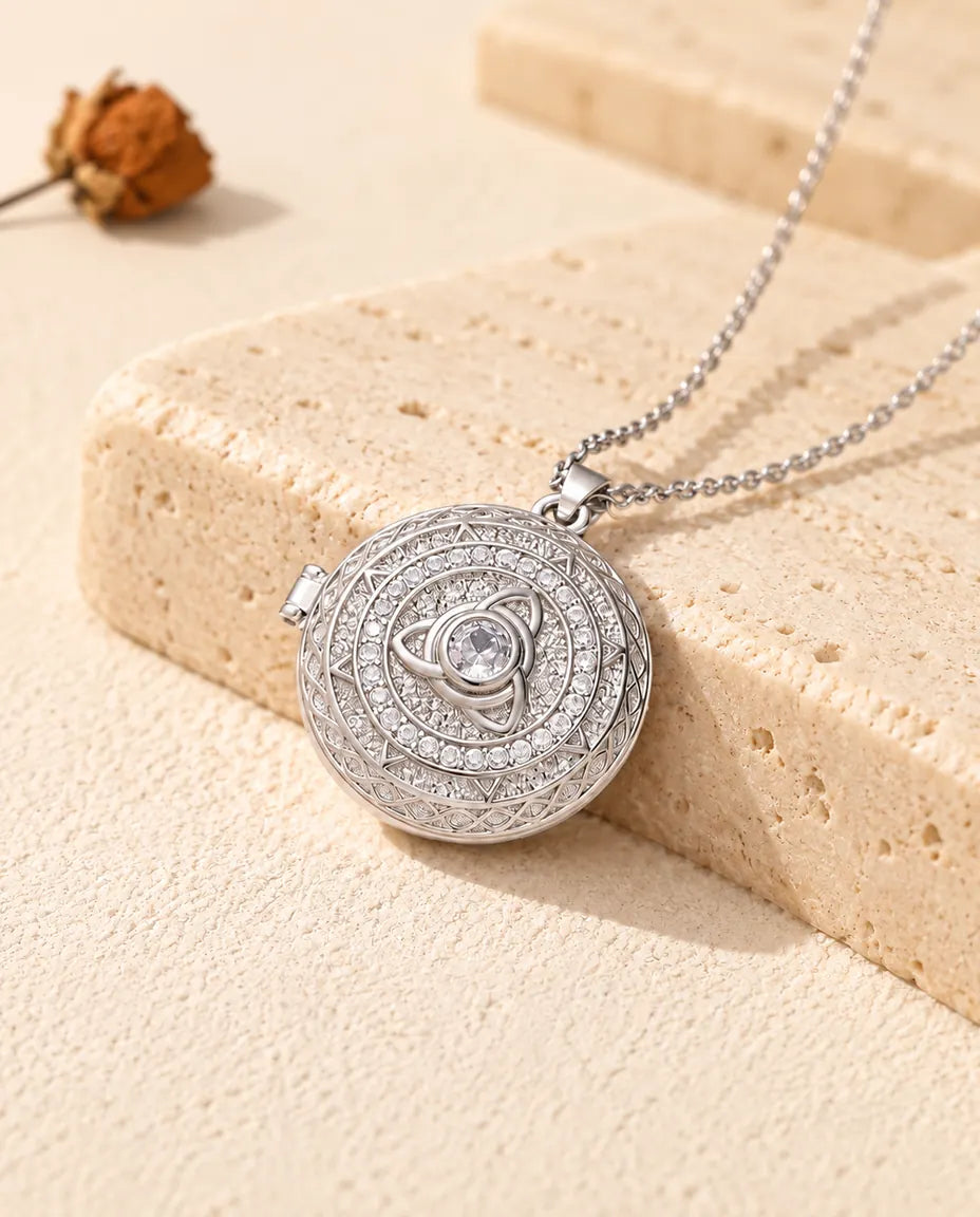 Collier médaillon photo rond personnalisé à nœud triquetra argenté et zircons posé contre un bloc de travertin