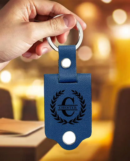 Main tenant le porte-clés en similicuir bleu avec monogramme