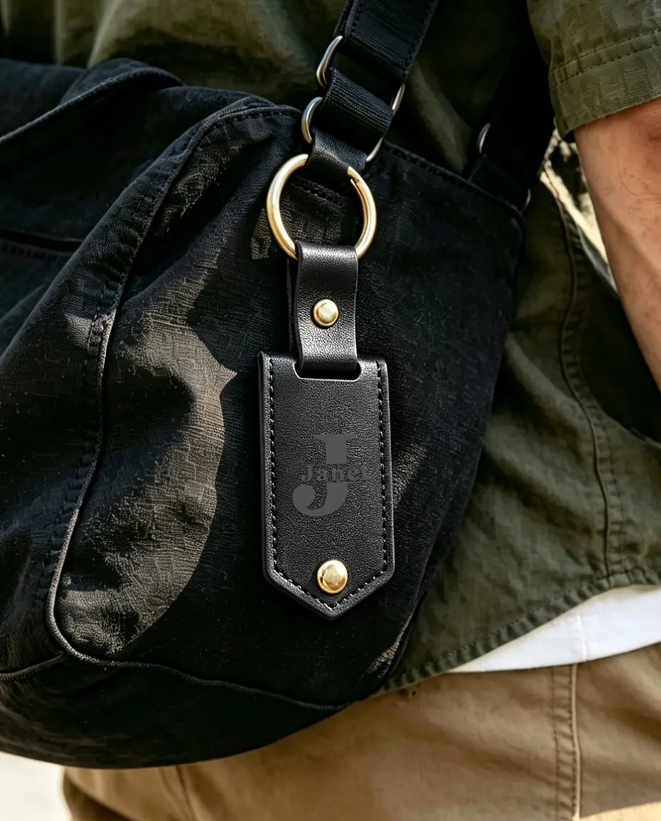 Porte-clés en similicuir noir gravé accroché à un sac