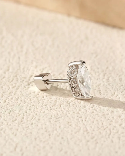 Puces d’Oreilles Moissanite Marquise en Argent 925 - posée sur une surface claire texturée près d’une dalle de travertin