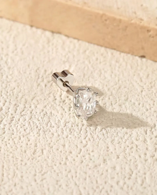 Puces d’Oreilles Moissanite Taille Radiant en Argent 925 - posée sur une surface claire texturée près d’une dalle de travertin