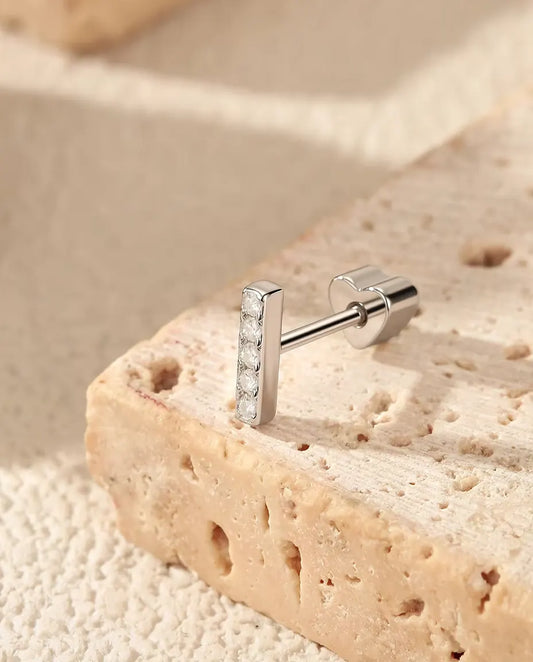 Puces d’Oreilles Barrette à Cinq Moissanites en Argent 925 - posée sur le rebord d’une dalle de travertin