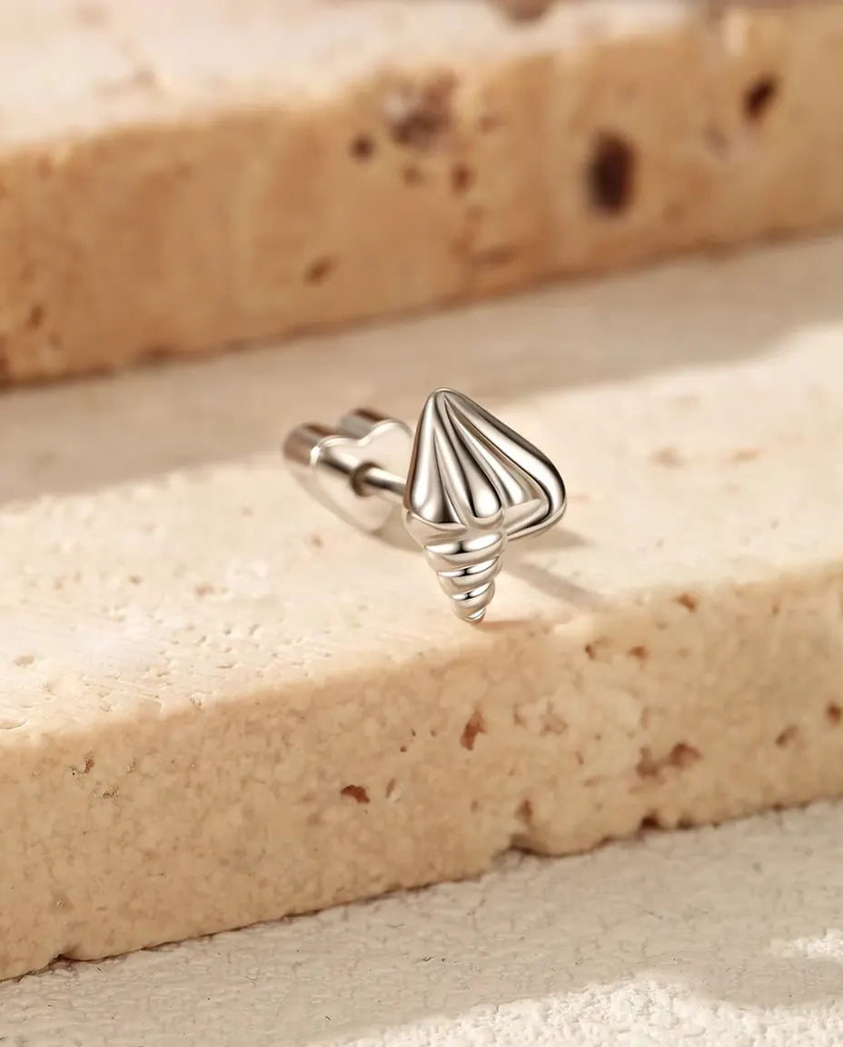 Puces d’Oreilles Coquillage en Spirale en Argent 925 - posée sur le rebord d’une dalle de travertin