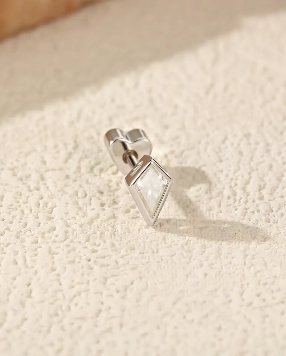 Puces d’Oreilles Moissanite Cerf-Volant en Argent 925 - posée sur le côté sur une surface claire texturée, fermoir en forme de cœur sur la tige