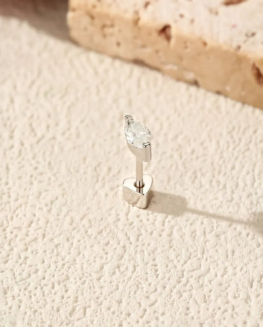 Puces d’Oreilles Moissanite Marquise en Demi-Serti Clos - debout sur son fermoir en forme de cœur, sur une surface claire texturée