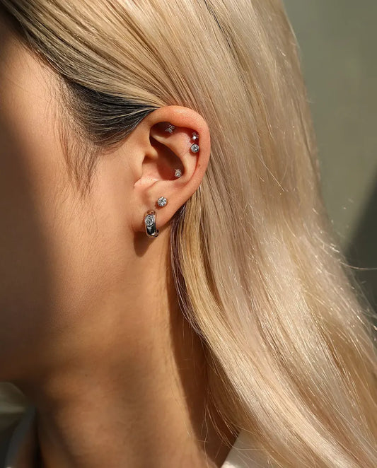 Puces d’Oreilles Moissanite Ronde à Arc Latéral en Argent 925 - portée par un mannequin, plan plus large de l’oreille et du cou